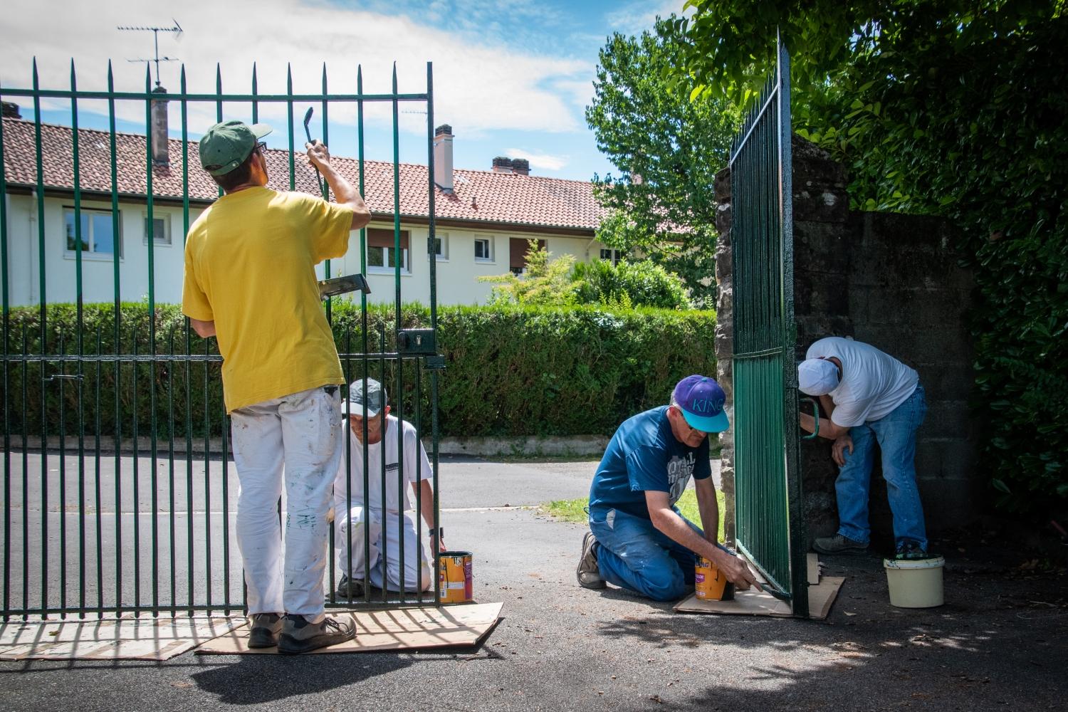 Des ouvriers repeignent un portail