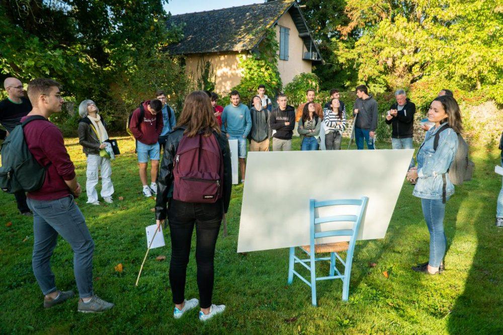 Deux étudiants présentent des esquisses dans les jardins du Foyer.