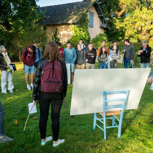 Deux étudiants présentent des esquisses dans les jardins du Foyer.