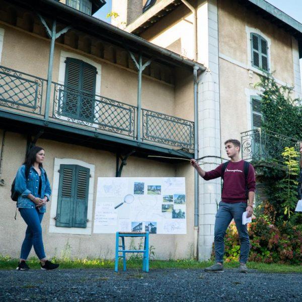 Deux étudiantes et un étudiant présentent un projet d'aménagement dans la cour de l'ancienne batisse.